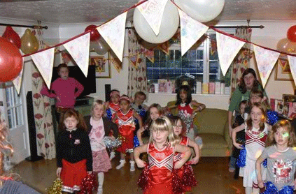 Children in costumes at a themed birthday party with decorations, including balloons and banners.